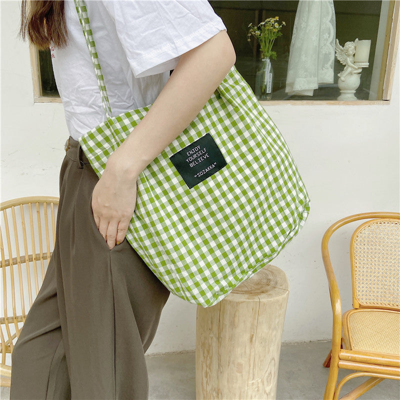 Black grid-pattern canvas shoulder bag with a magnetic buckle closure